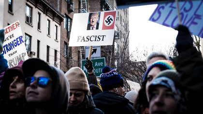 A shallow focus photo of a person holding a Donald Trump sign during an immigrant rights protest in the West Village, New York City, USA