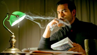 Homem pensativo com livro sentado em quarto esperando a inspiração