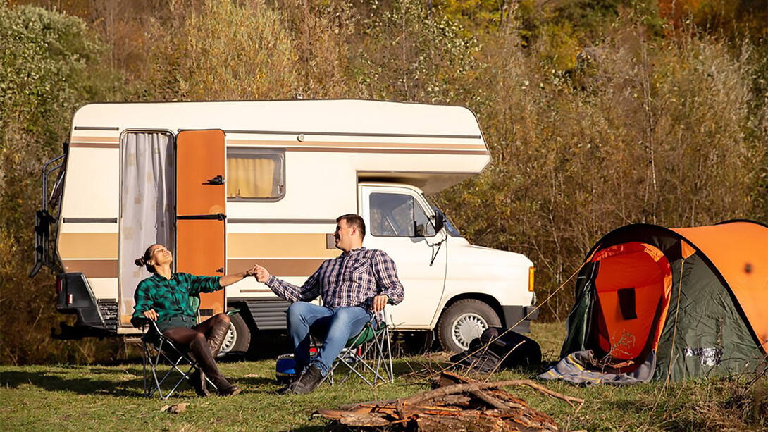 A couple in love relaxes on camping chairs, soaking in the beautiful weather and embracing van life