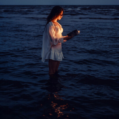 Mulher lê um texto sagrado em meio às águas do mar