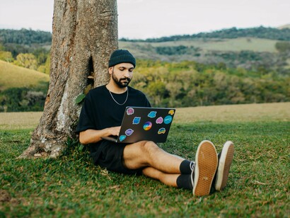 Com o computador no colo, um profissional desenvolve suas atividades fora do ambiente tradicional de escritório. O artigo propõe uma reflexão sobre as oportunidades e os desafios trazidos pelos novos modelos de trabalho