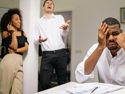 Homem sofre com a fofoca no ambiente de trabalho. O assédio moral no trabalho pode ter profundas consequências emocionais para as vítimas, afetando significativamente seu bem-estar psicológico