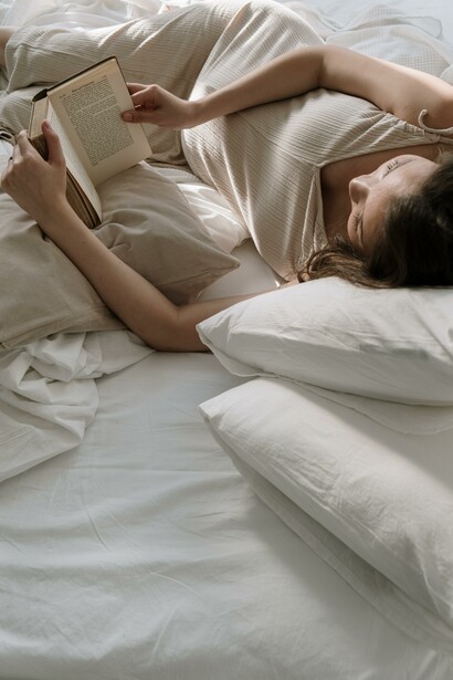 A woman relaxing and reading in her bed