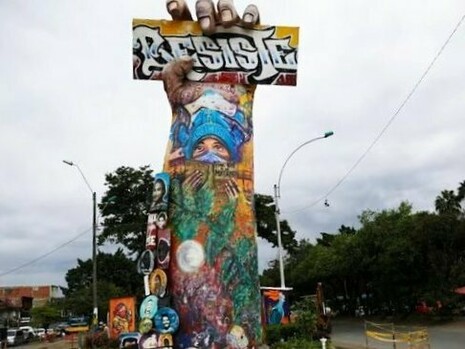 O Monumento a la Resistencia se ergue em meio ao movimento cotidiano de Cali, no local conhecido como Puerto Resistencia. Construído no próprio território das mobilizações, o memorial mantém a lembrança do estallido social integrada à paisagem e à vida da cidade. A obra deixou de ser apenas uma escultura para se tornar também lugar de memória, debate e disputa sobre o significado daquele período ocupando o espaço onde a mobilização popular ganhou uma de suas expressões mais fortes