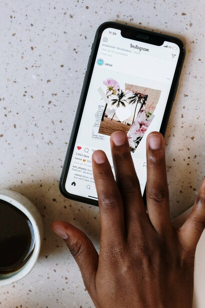 A person using social media whilst drinking a mug of coffee