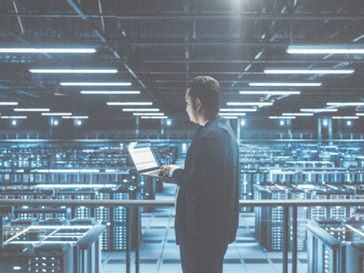 A data center engineer monitors performance metrics on a tablet, managing a vast server farm dedicated to quantum information processing and stochastic resonance synergies