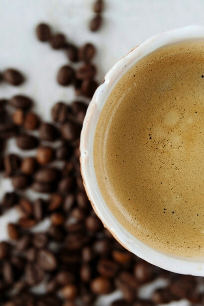 Top-down view of a cup of coffee with coffee beans scattered around