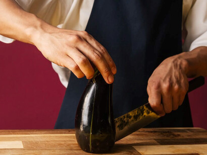In the culinary realm, a chef expertly slices through eggplants, crafting a sensational rendition of "Hünkar Beğendi"