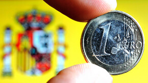Moneda de un euro con la bandera española al fondo