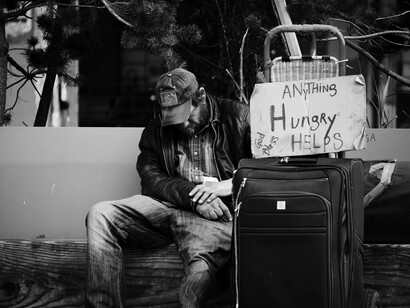 A homeless person in Seattle, USA, sitting on the sidewalk with belongings