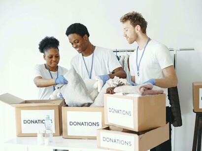 A trio smiling as they place donations in boxes as part of their act of kindness