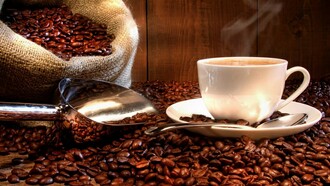 Taza de café humeante junto a un saco de granos de café