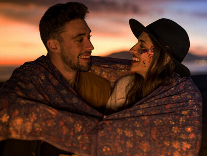 Romance with a young couple cozily wrapped in a blanket on the seashore, symbolizing love and unity in their relationship