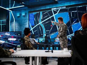 Soldiers overseeing digital surveillance and operational data on screens in a military control room