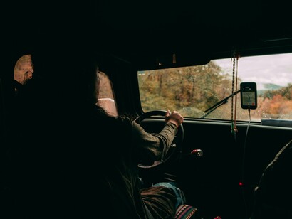 The driver grips the wheel while a navigation screen glows beside him, capturing the balance between modern convenience and the still-necessary act of paying attention to the journey
