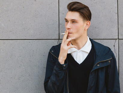 A young man lighting up a cigarette outside