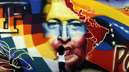 Una niña delante de un mural en Caracas que recuerda a Chávez
