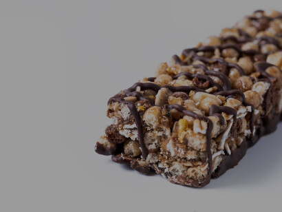 Healthy muesli bars with nuts and seeds displayed on a table, shown in close-up with ingredient flat lays on a white backgroun