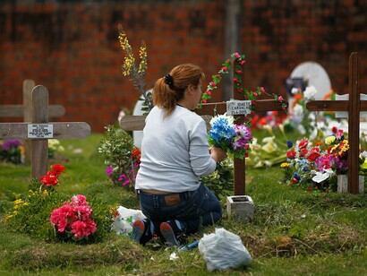 Una mujer lleva flores al cementerio