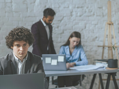 A man working on a laptop in a call-center environment, representing the often invisible “ghost workers” behind AI systems