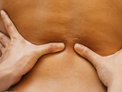 Mani di un osteopata che manipolano la schiena di un paziente