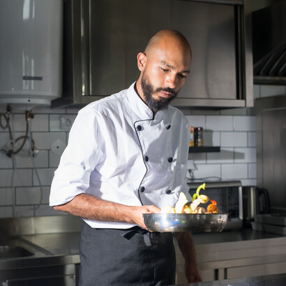 Chefe de cozinha flamba alimentos em uma frigideira