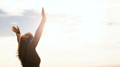 A person with arms raised greeting the limitless sky as they express they freedom