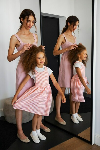 A girl and her mother standing in front of a mirror, sharing a moment of reflection and connection