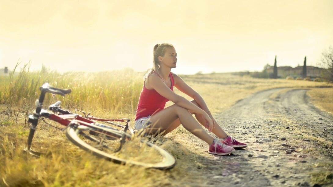Mujer descansa bajo el sol luego de un recorrido en bicicleta