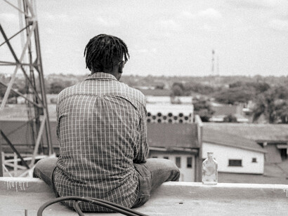 Homem na beira de prédio. Olho para o patamar de cima e reparo num homem encostado ao corrimão, que passa primeiro a perna direita e depois a esquerda e num segundo fica do lado de fora