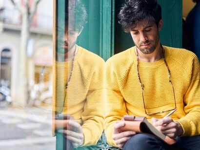 A thoughtful man writes in his diary beside the window on a peaceful autumn afternoon