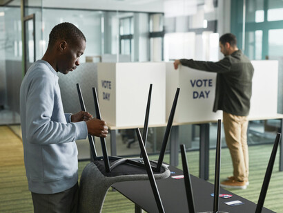 Man holding a chair while preparing a polling station for election day, representing the democratic process