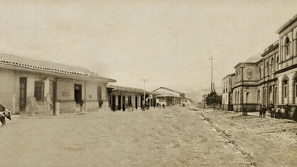 Composición fotográfica elaborada a partir de la fusión de tres imágenes antiguas de Cartago, tomadas antes del terremoto de 1910. La fotografía de la izquierda, capturada por Philip y Amelia Calvert, muestra la casa tradicional de Anacleta, cuando albergaba la tienda El Irazú de don Felipe Martín en 1910. Las otras dos, de autor desconocido, corresponden a la Escuela de Párvulos y al hotel Estrella del Norte (a la derecha). Fusión fotográfica realizada por Florentino Leiva Ortega, 2025