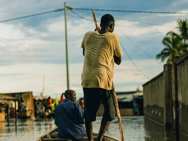A resident transporting people through flood-affected streets, symbolising the need for stronger climate adaptation and disaster preparedness
