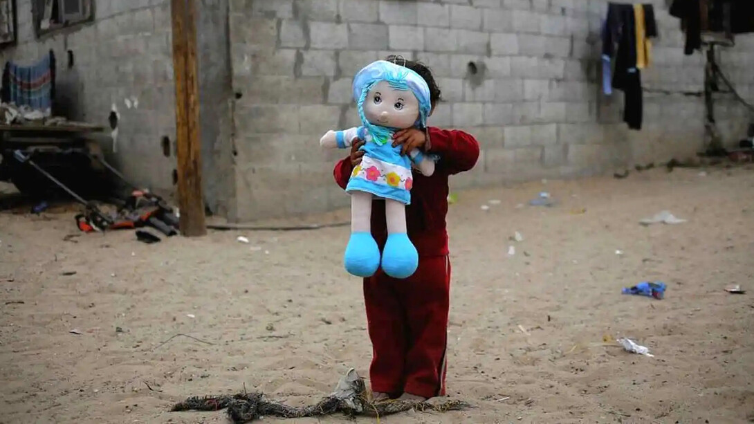 Una niña en situación de pobreza posa con la muñeca que recién le han obsequiado los servicios asistenciales