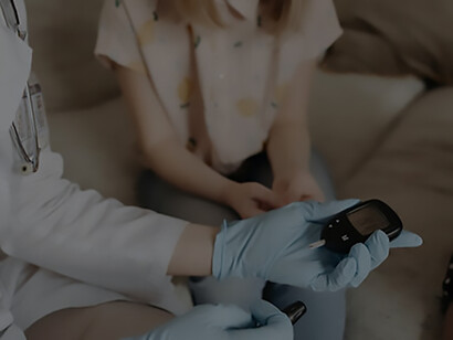 In a compassionate scene, a doctor employs a device to measure the blood sugar levels of a young girl, demonstrating dedicated healthcare with a gentle touch