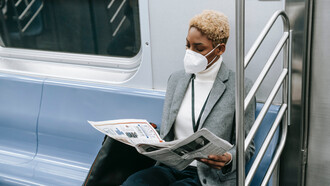 Professora lê manchetes do jornal no metrô