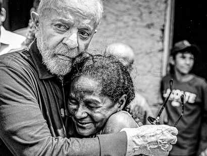 Lula fundido en un emotivo abrazo con una mujer residente durante una visita comunitaria