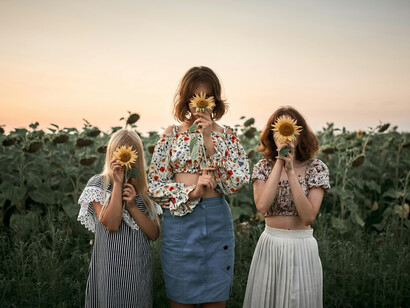 Tres muchachas se tapan el rostro con girasoles