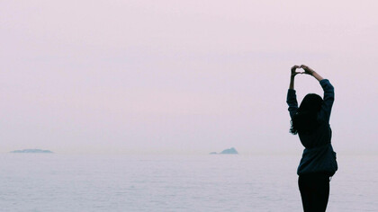 A woman in a peaceful setting is expressing her self-love to the world