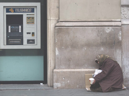 Mujer sin techo mendiga junto a un cajero automático