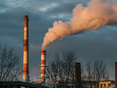 Dense fogs of industrial smoke rising above the city, reflecting the mounting pressure human activity places on Earth's ecosystems