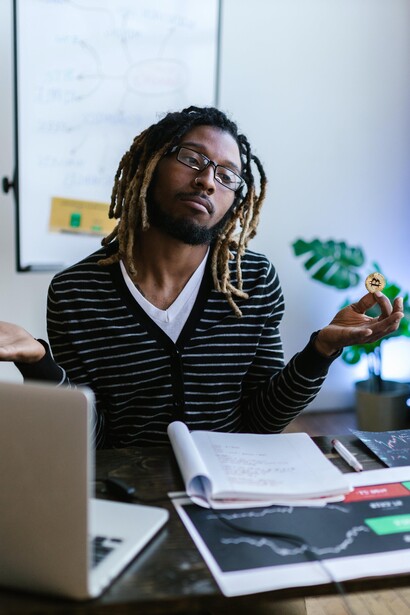 Analista financeiro mostra uma moeda física de bitcoin