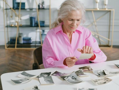 Mulher observa fotos antigas. Eu, por vezes, sinto o cheiro dela, não sei como e nem porquê, mas sinto. Outras tantas vezes, chego a sentir seu delicado toque em meu rosto com um sorriso, me dizendo para seguir em frente