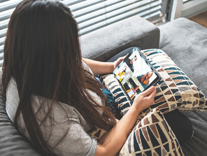 Woman selecting a film from a streaming platform on her tablet, enjoying the convenience of digital entertainment