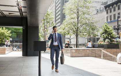 Businessman walking away from the office while speaking on the phone