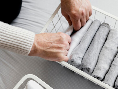 A woman organizing her closet with a minimalist approach and a carefully curated capsule wardrobe