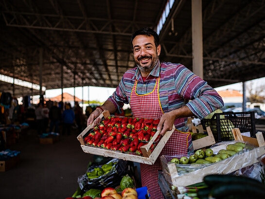 A farmer's market vendor displaying a crate of fresh strawberries, ready for customers to enjoy