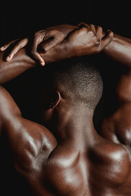 Back view of a shirtless man posing to showcase his muscles and physical fitness