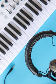 The essence of amapiano music with an image of headphones held by a male against a backdrop of musical keys and a piano, capturing the soulful rhythm and vibe of amapiano